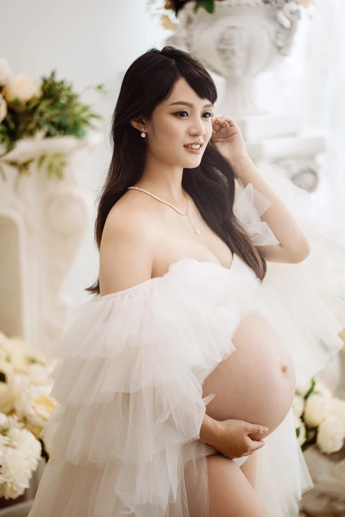 0000 0003 1 孕婦攝影,芷妤穿白色薄紗坐在花藝背景前並抱著孕肚