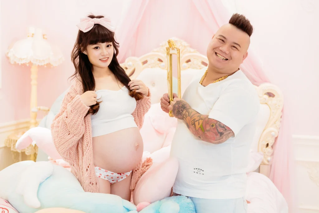 0000 0021 1 夫妻寫真,小胖與芷妤在粉紅色場景中合照並呈現孕肚