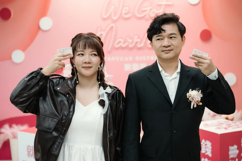 桃園戶政事務所婚攝，李小姐與蔡先生在粉色背板前手持小型紀念道具合照