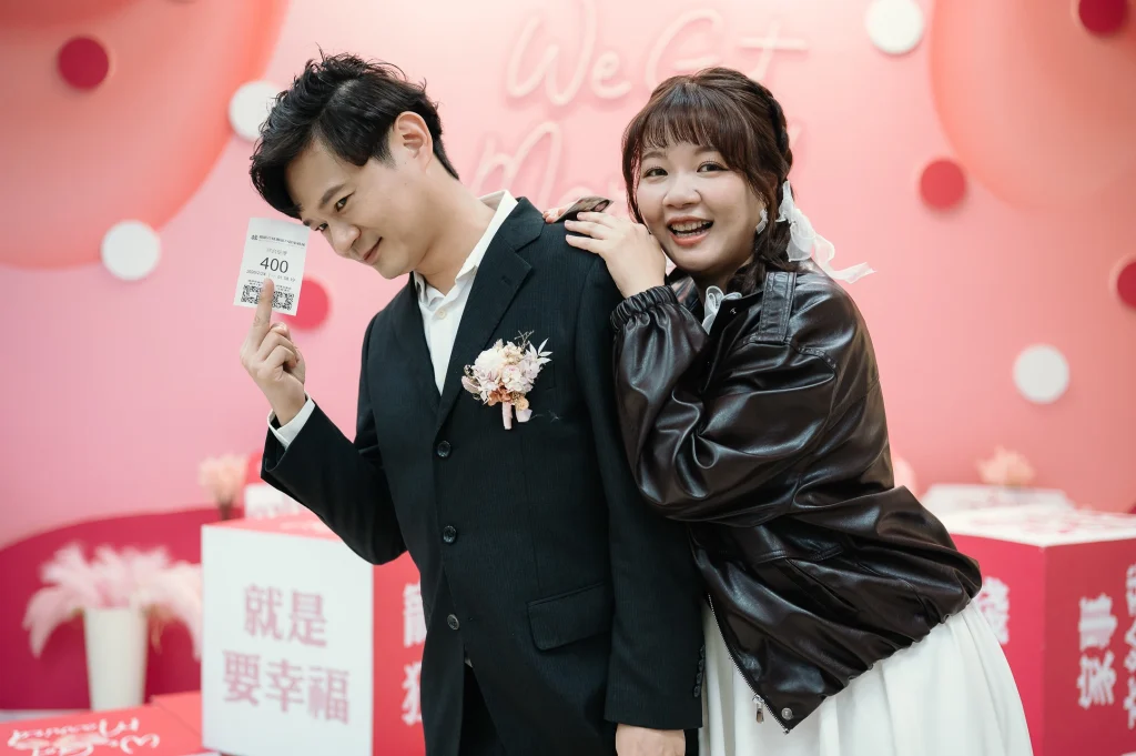 登記結婚婚攝作品，李小姐與蔡先生在婚禮背板前手持登記相關卡片合照