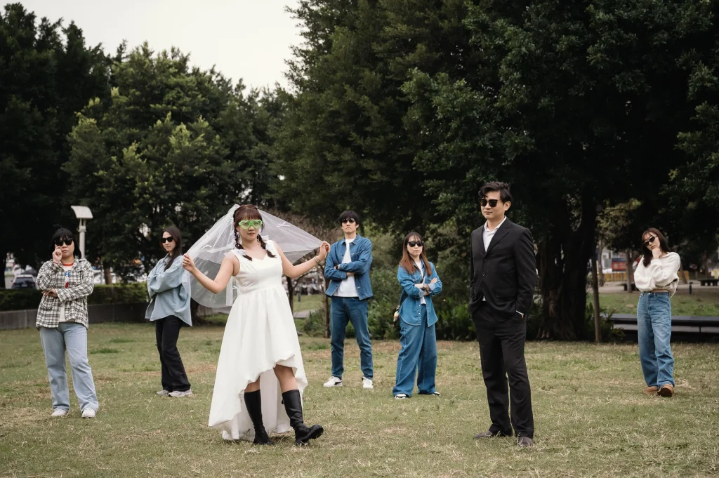 桃園戶外結婚攝影，新娘穿著白色洋裝與頭紗站在草地中央，親友在周圍互動