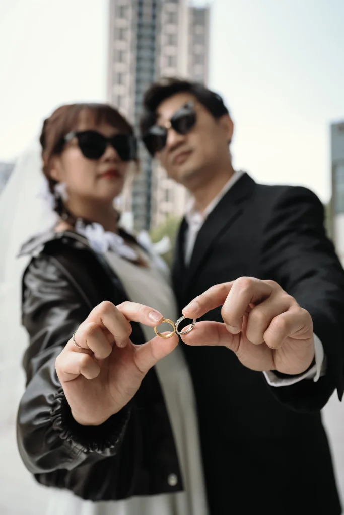 桃園結婚寫真，新人手持戒指或紀念小物靠近鏡頭展示，人物在後方失焦