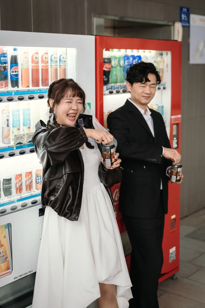 桃園生活感婚攝，李小姐在飲料販賣機旁操作或取用飲品，蔡先生在旁陪伴