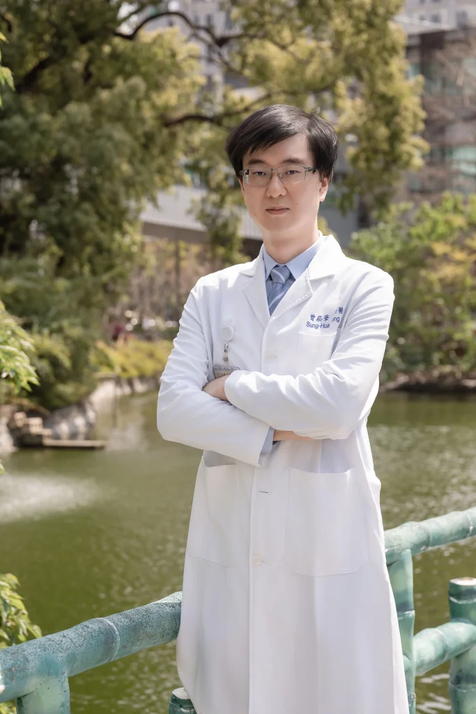 0317 0028 醫療團隊形象照,白袍醫師抱胸站在樹木與湖畔背景前
