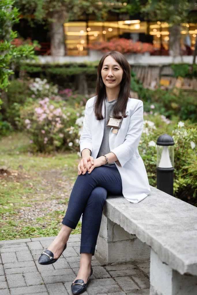 醫師形象照，女性醫師穿白袍坐在戶外水景旁