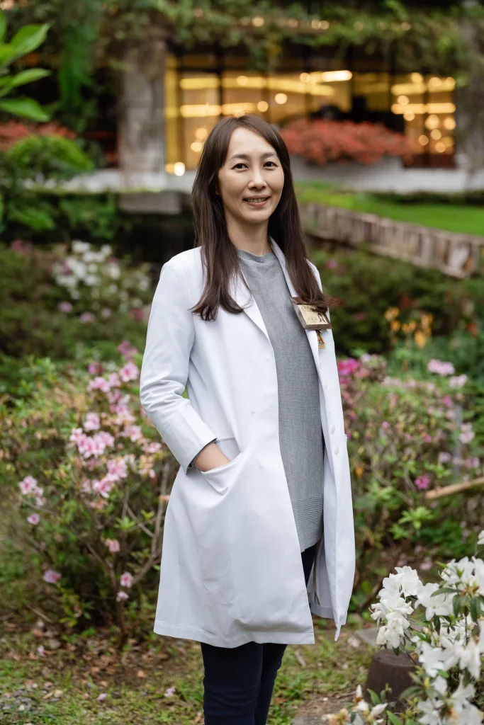 人物形象攝影，女性醫師穿白袍站在戶外花叢旁