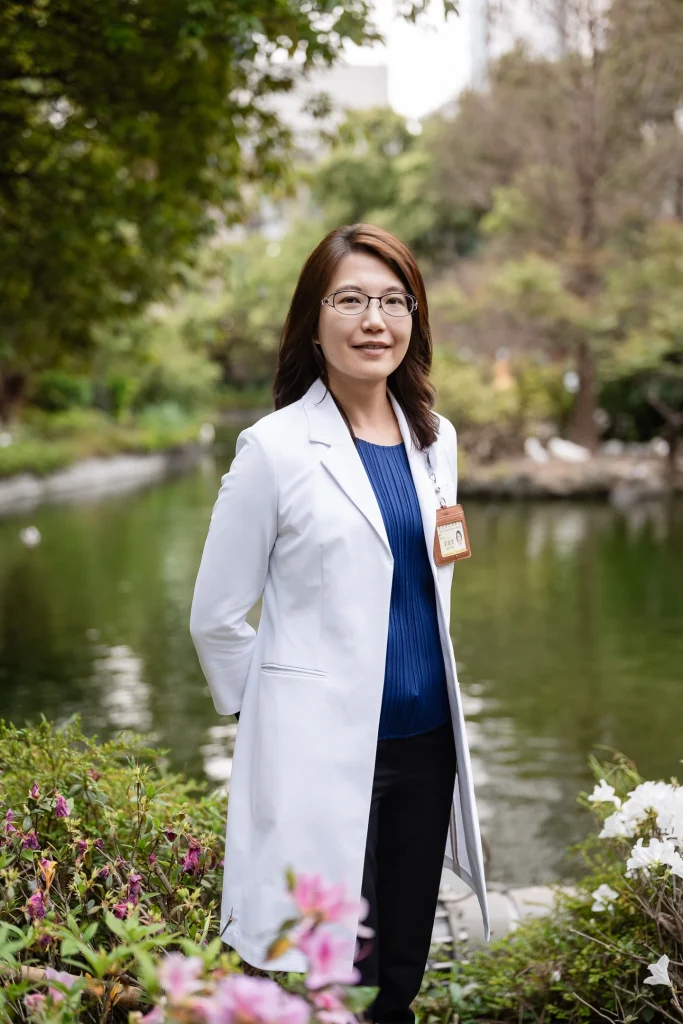 醫療形象攝影，女性醫師穿白袍站在湖畔花園旁