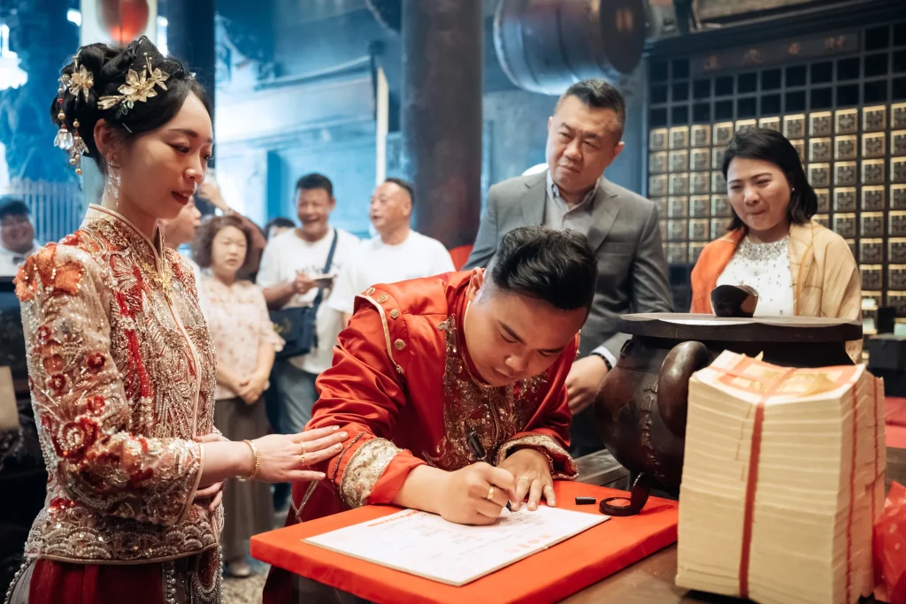 北港婚禮證書簽署攝影，新郎穿著傳統服飾在紅色桌前書寫文件