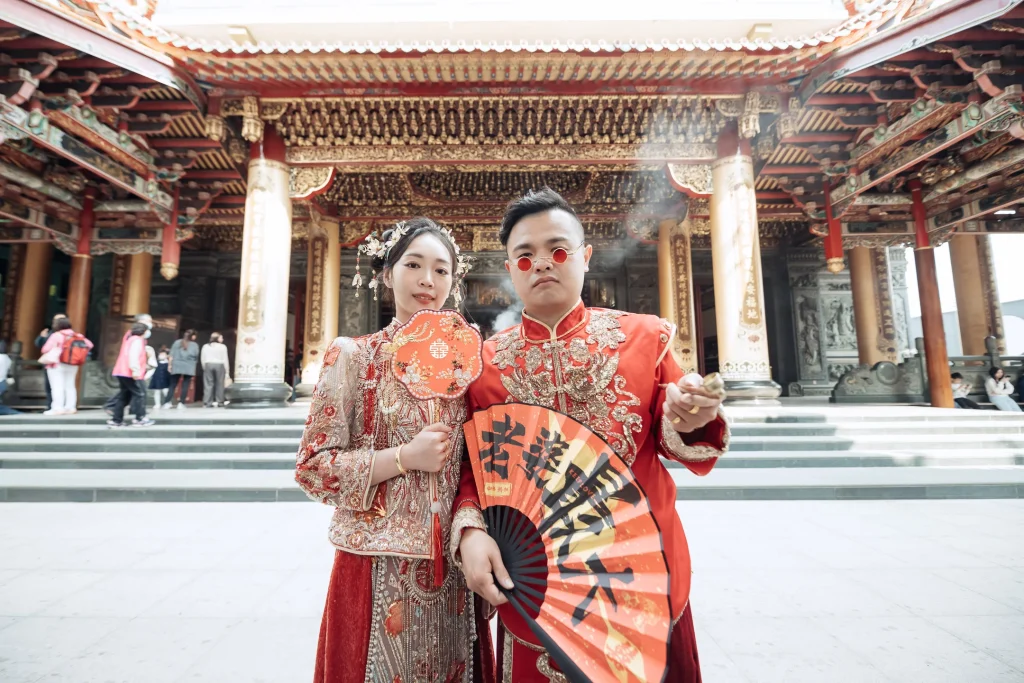 北港婚禮傳統服飾攝影，新郎新娘在武德宮牌樓前手持紅扇合照