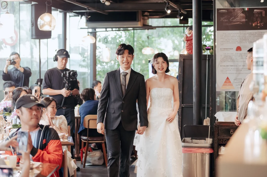 台北婚禮進場攝影，Farn 與 Tyni 牽手走入室內婚宴場地接受賓客歡迎