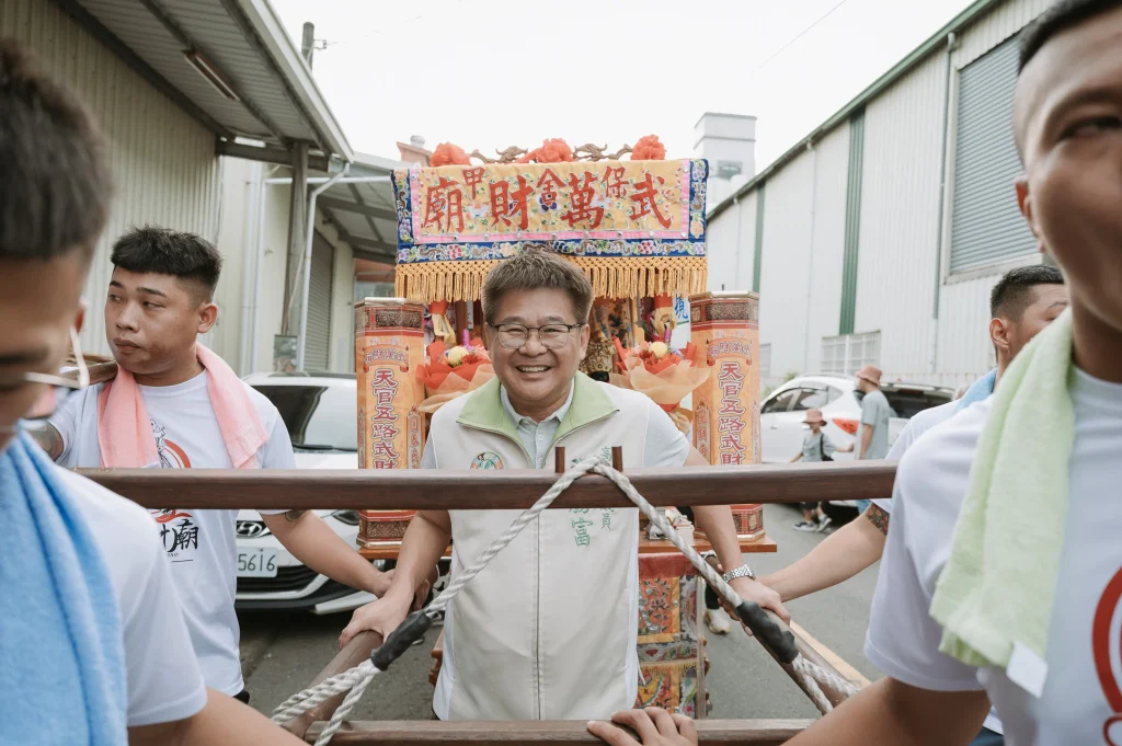 宮廟遶境隊伍，多位人員在街道上合力抬著神轎前進